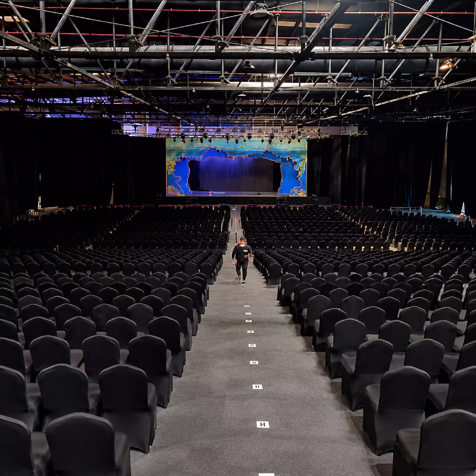 Large indoor event stage with professional lighting and rows of audience seating