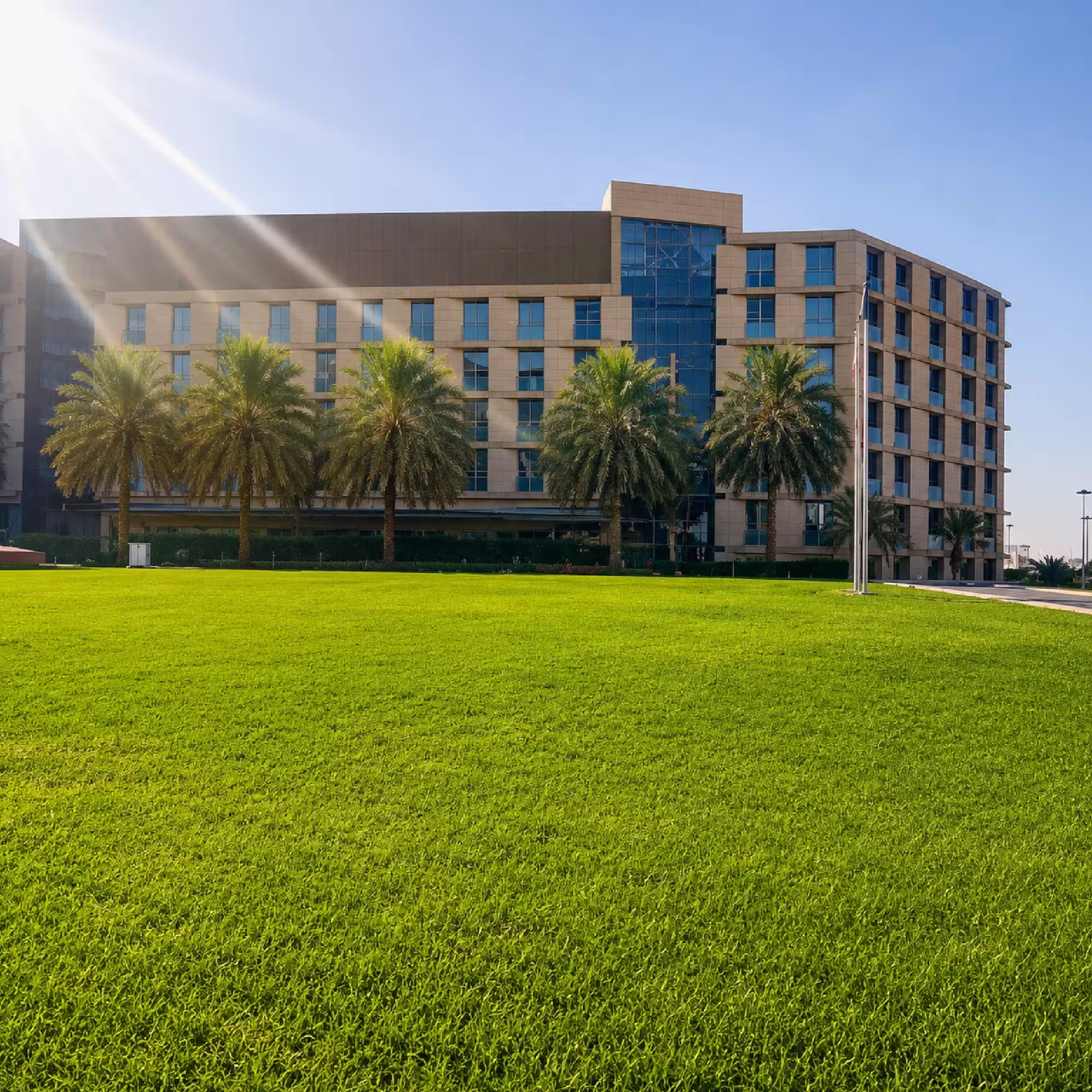 Modern large-scale building structure surrounded by landscaped grounds and palm trees in Dubai