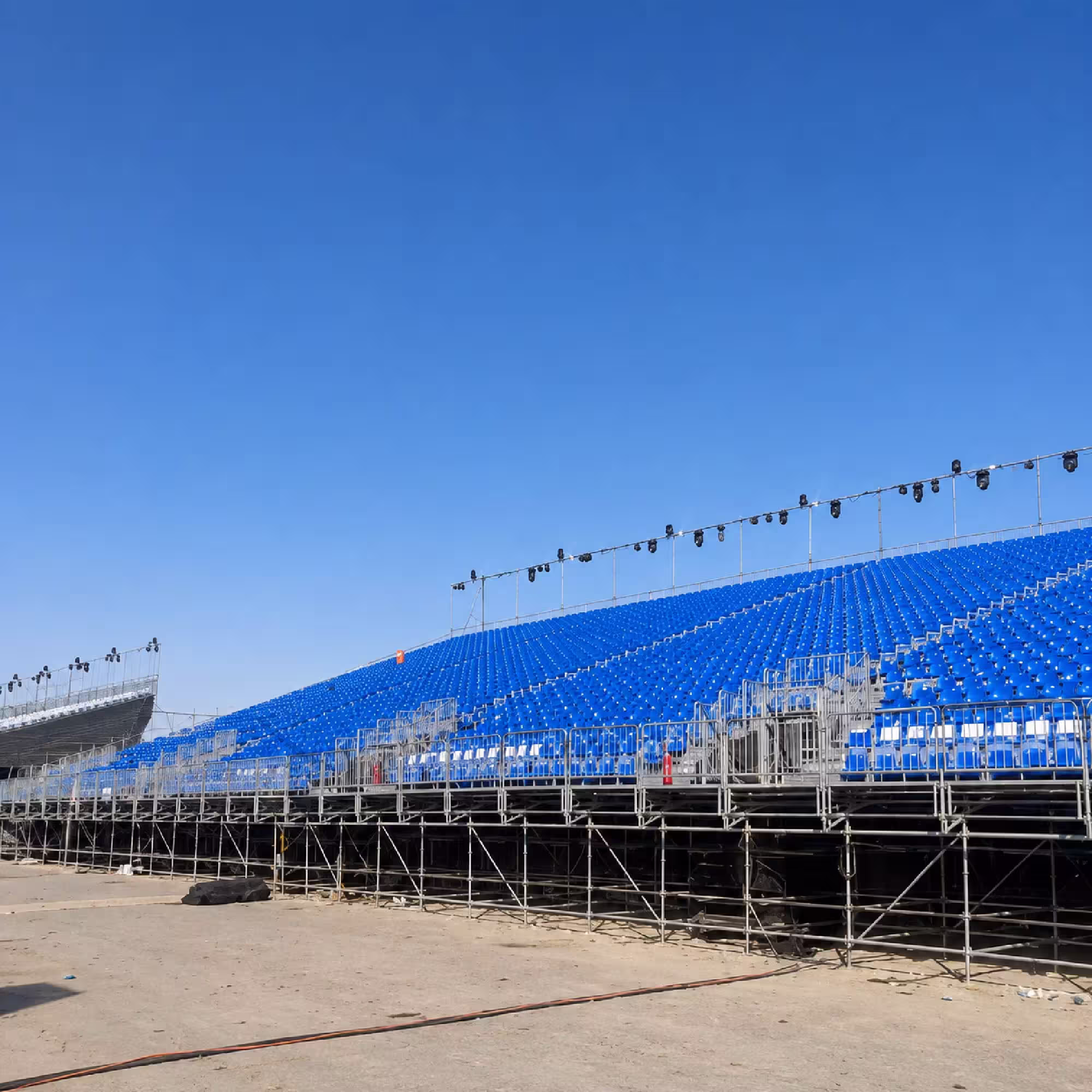 Large temporary grandstand with blue spectator seating and supporting scaffolding