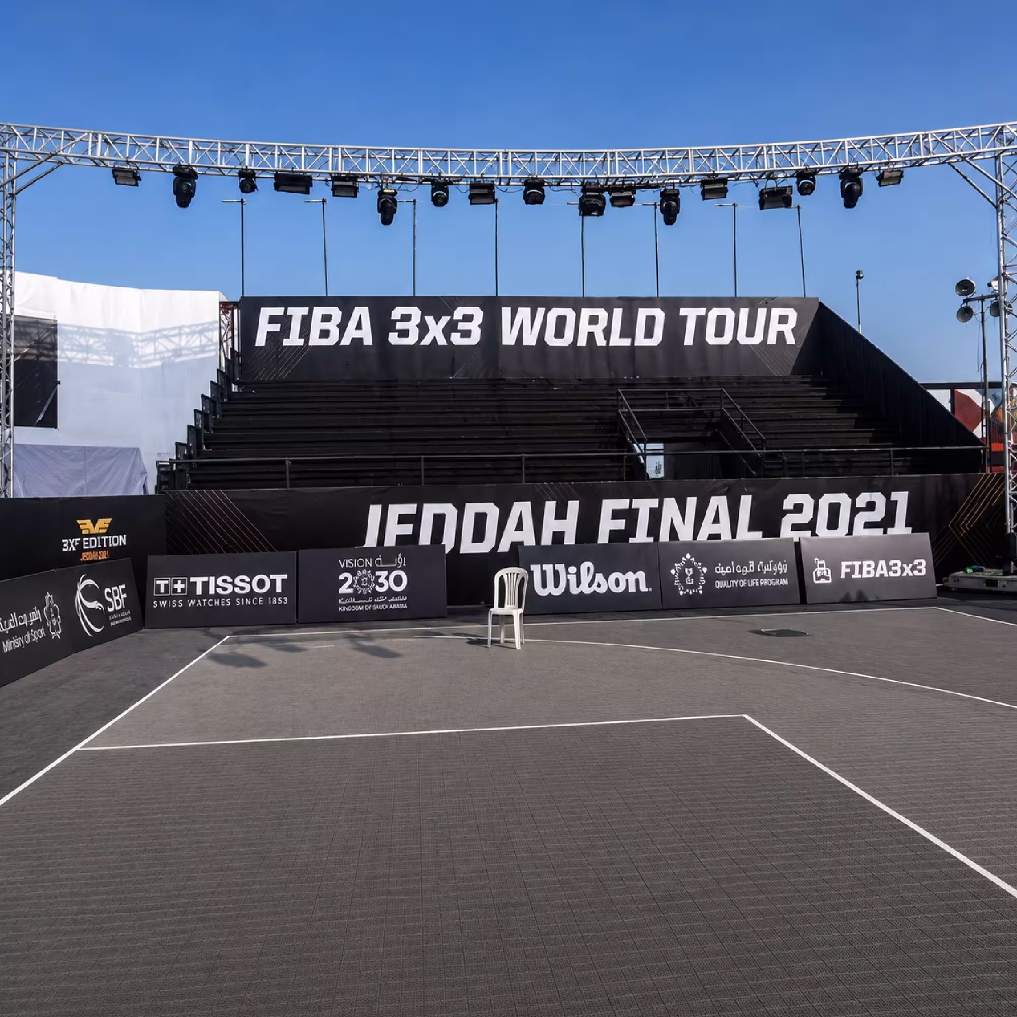 Temporary outdoor grandstand with tiered seating and professional lighting rig at a sports event