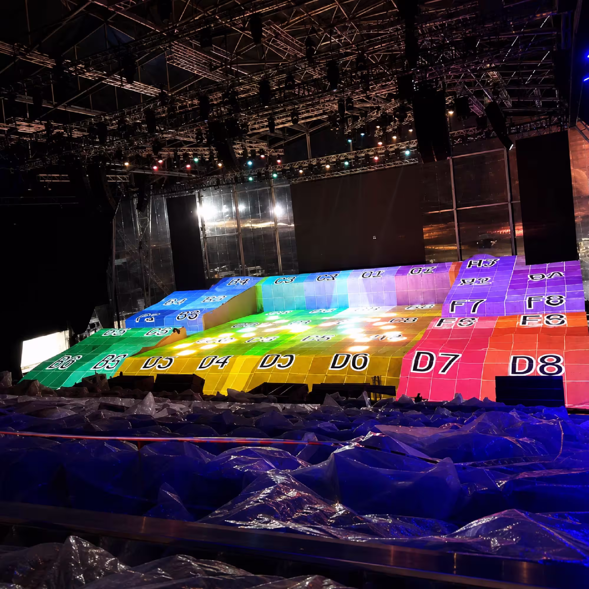 Large indoor event stage with colorful illuminated floor and professional lighting rig