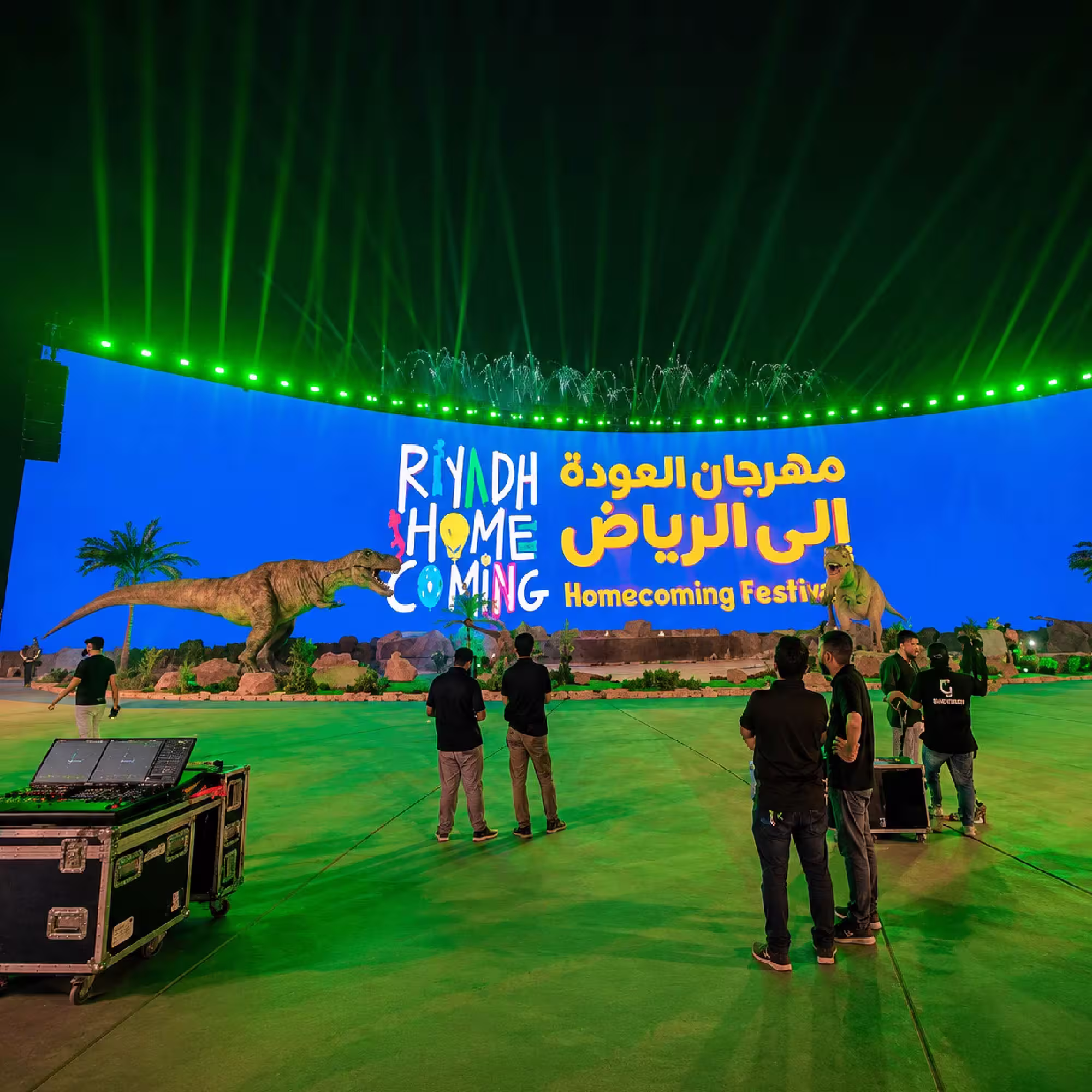 Large outdoor festival event with LED screen, dinosaur displays, stage lighting and event production equipment