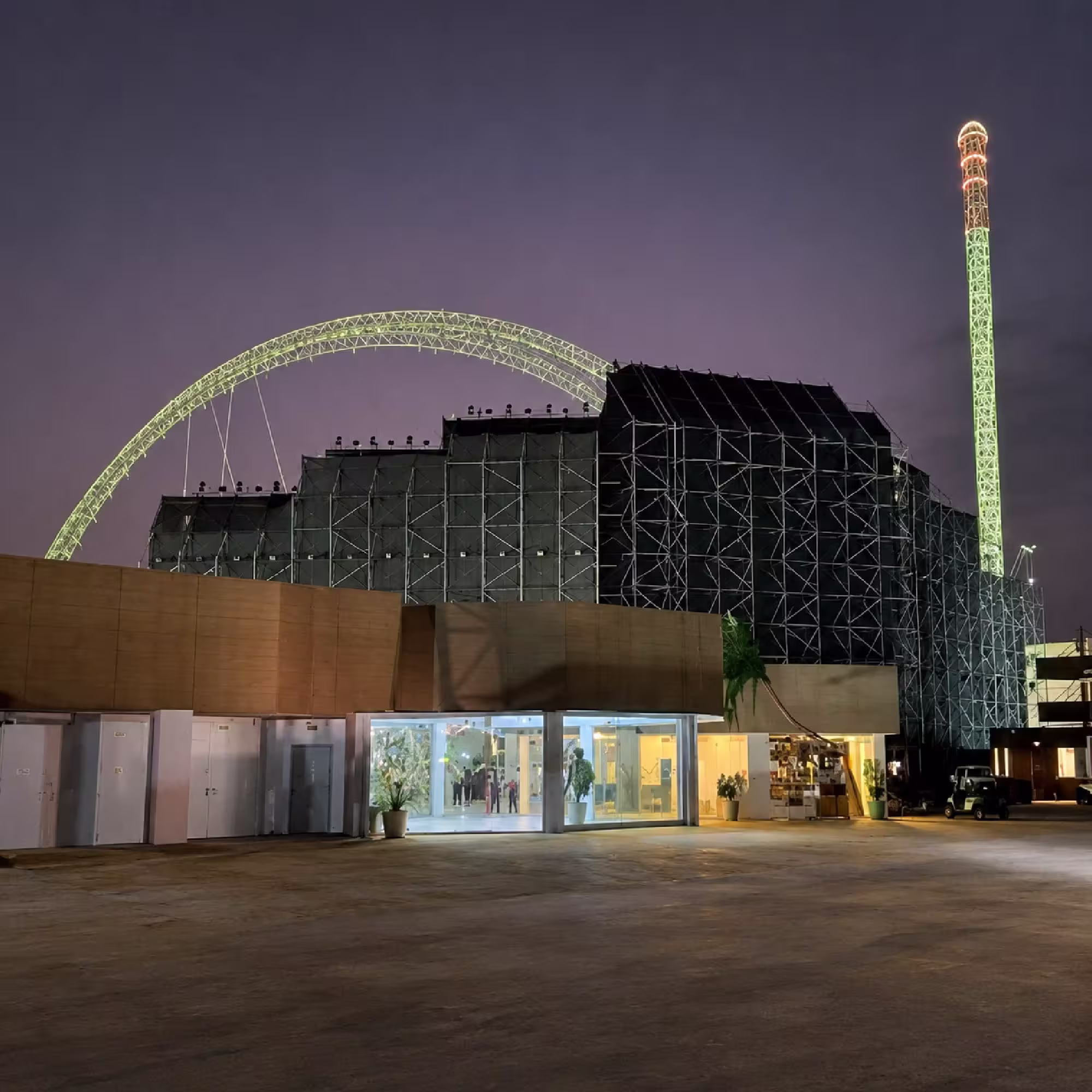 Large temporary scaffolding structure supporting an outdoor event venue at night