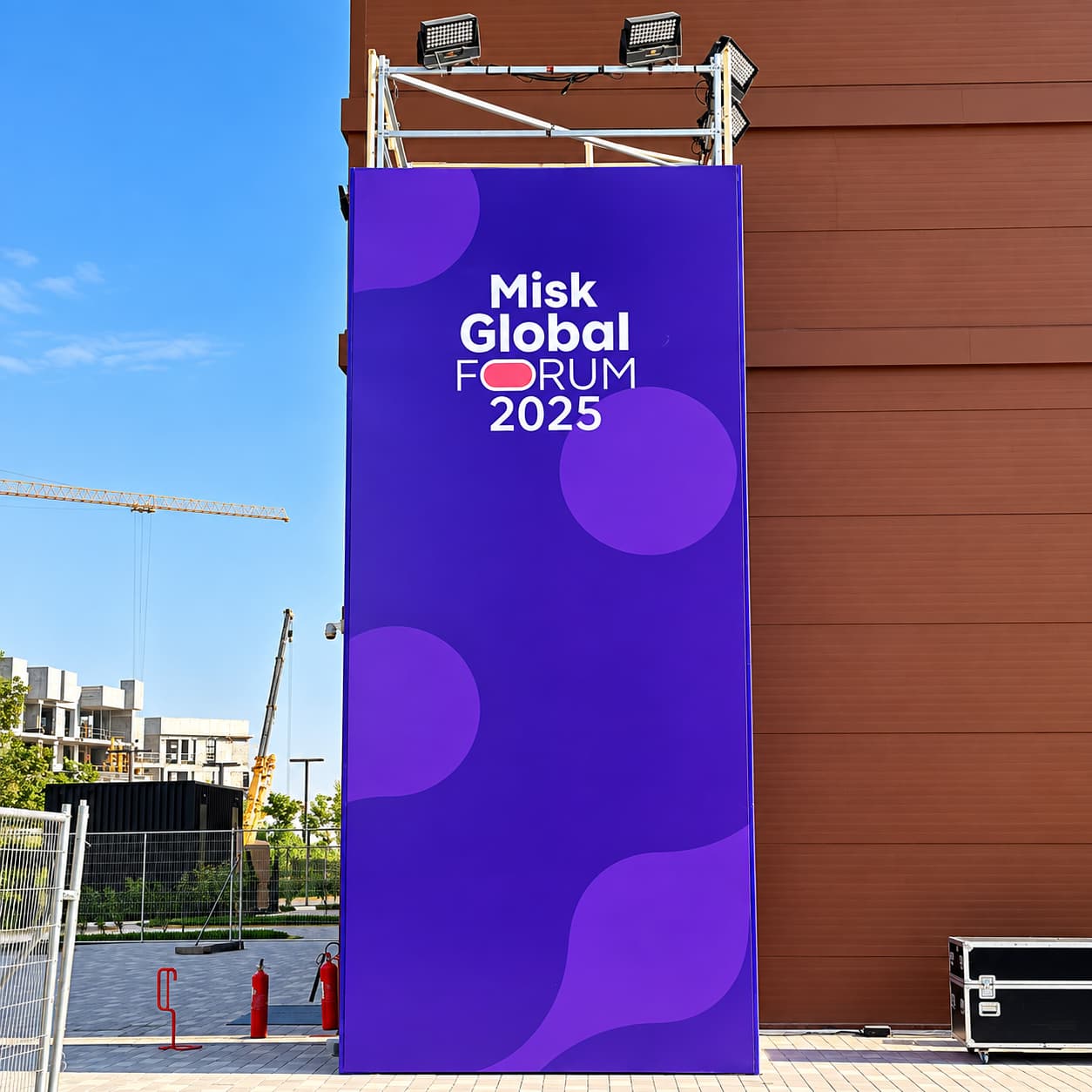Purple event branding tower featuring “Misk Global Forum 2025” signage with overhead LED lighting fixtures.