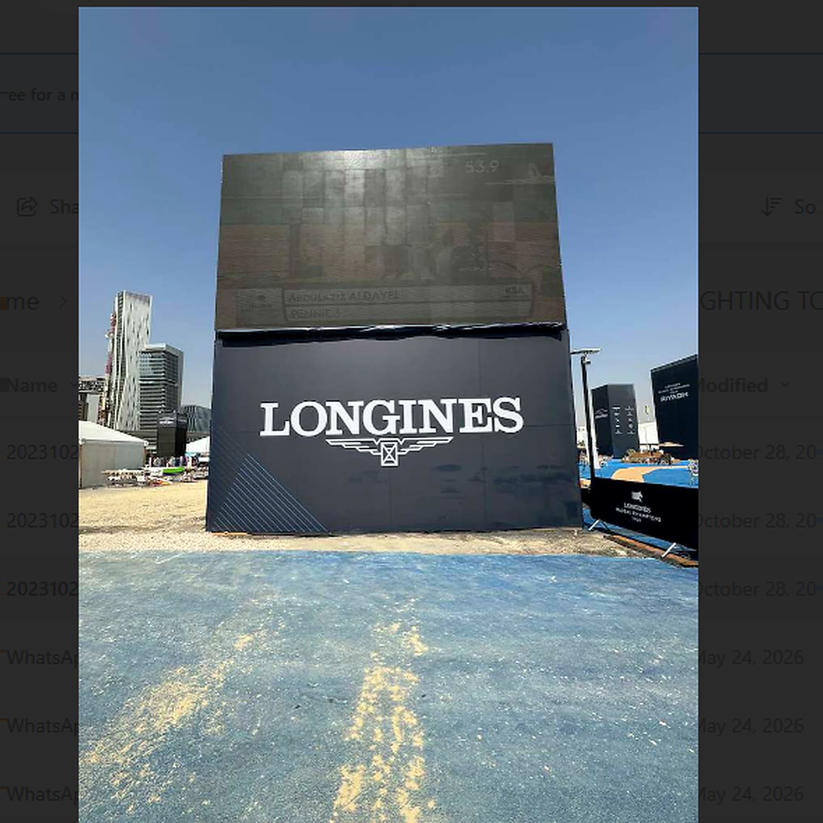 Temporary event structure featuring a large LONGINES branded display with black paneling at an outdoor event venue.