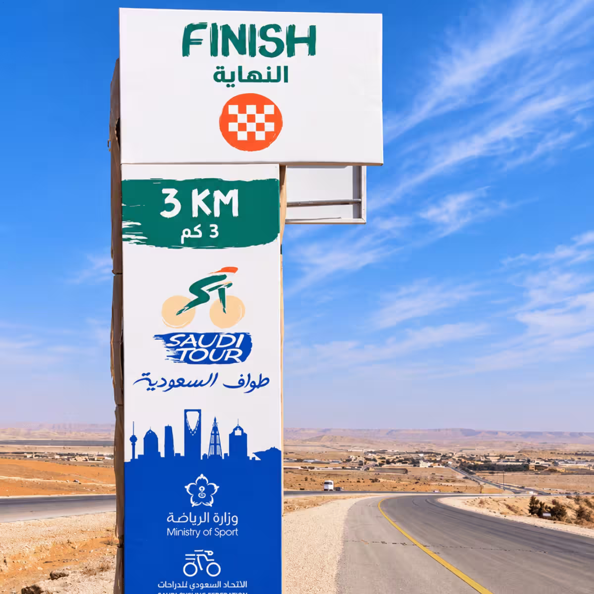 Saudi Tour finish sign showing 3 KM remaining on a desert road in Saudi Arabia.