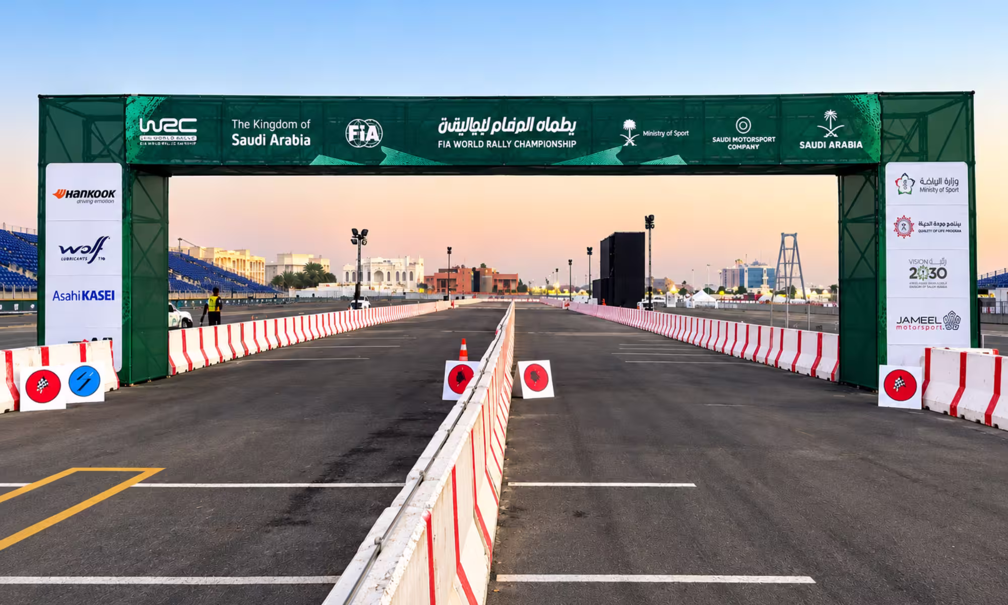 FIA World Rally Championship event arch over a race track in Saudi Arabia with red-and-white safety barriers.