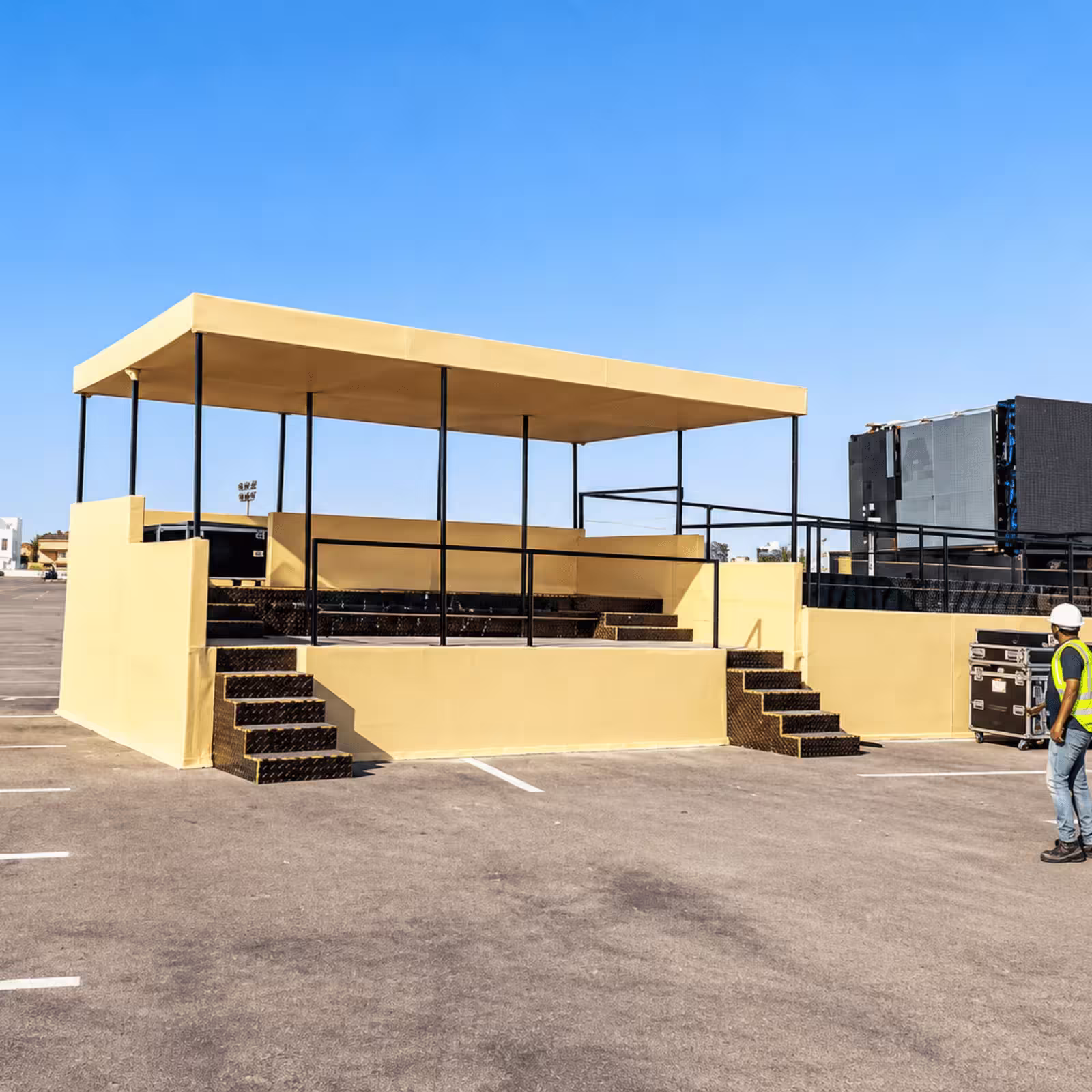 Outdoor event viewing platform with a covered seating area, stairs, safety railings, and event equipment.
