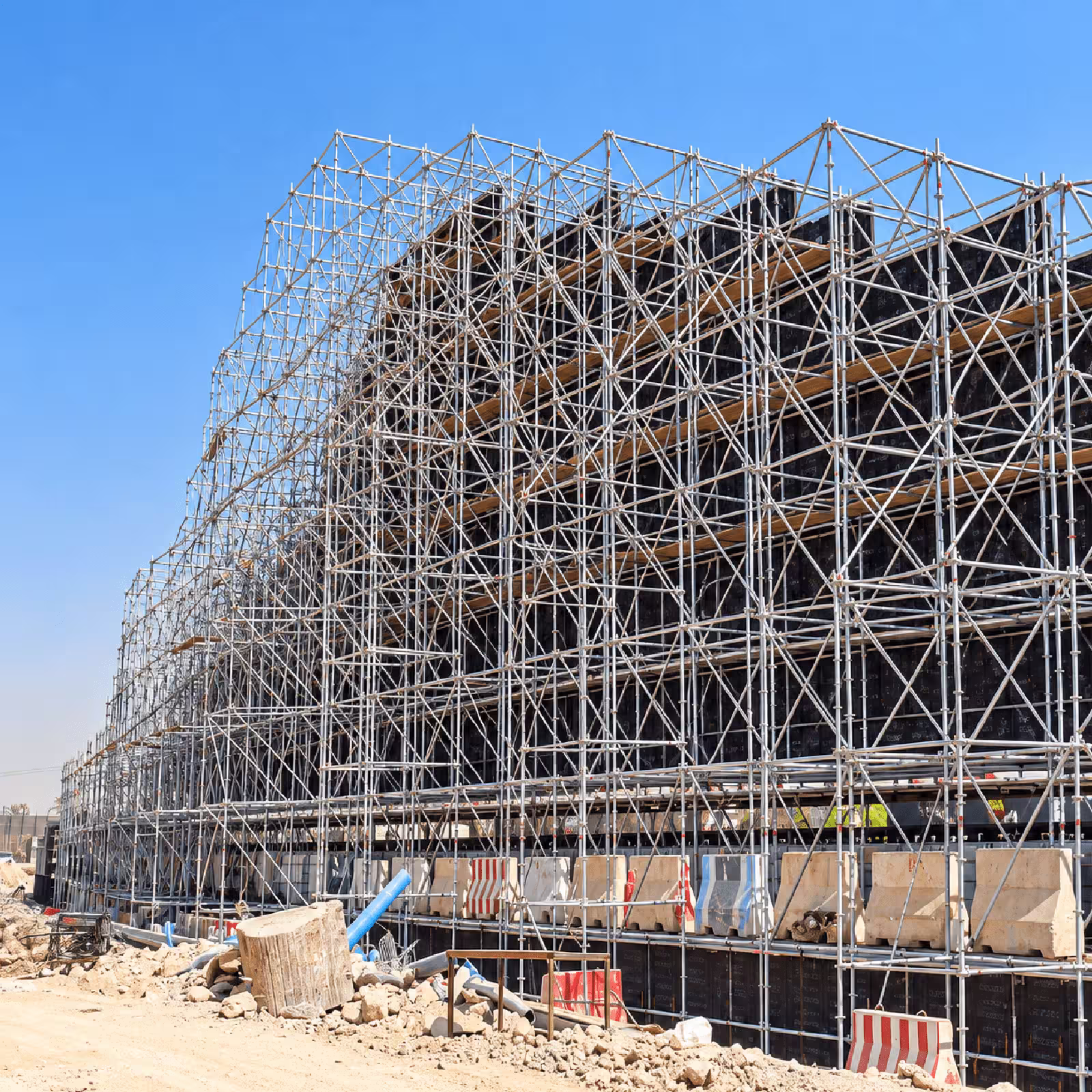 Large-scale ring lock scaffolding structure surrounding a construction project under a clear blue sky.