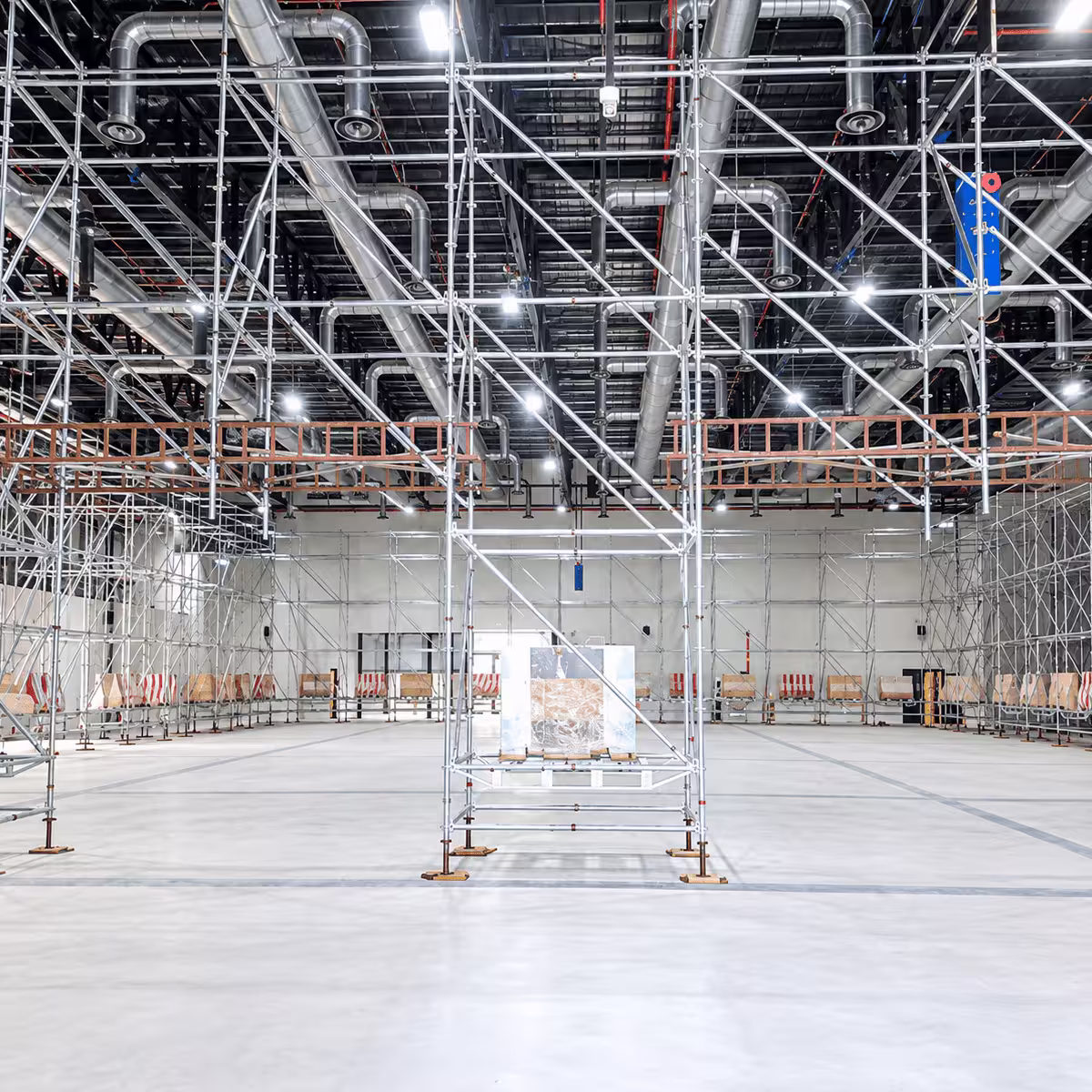 Indoor ring lock scaffolding system installed beneath industrial HVAC ductwork in a large facility.